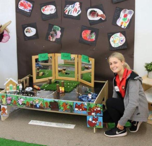 Chanel Turner kneeling beside a display of childrens' art